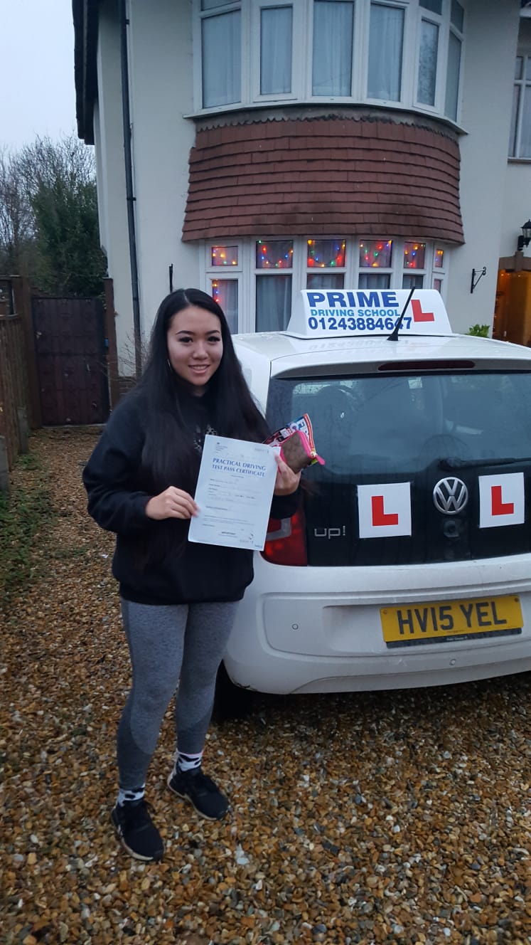pupil standing next to the driving instructors car with her certificate